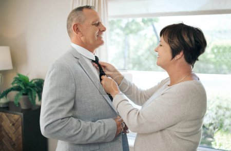 Téléchargez les photos : Tu peux redresser ma cravate ? une femme mûre aidant son mari à réparer sa cravate - en image libre de droit