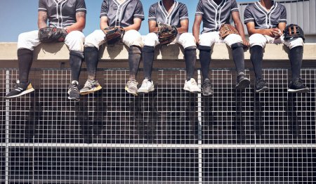 Foto de El siguiente en la línea para ganar el campeonato mundial. un grupo de hombres sentados en la parte superior del dugout y viendo un partido de béisbol - Imagen libre de derechos