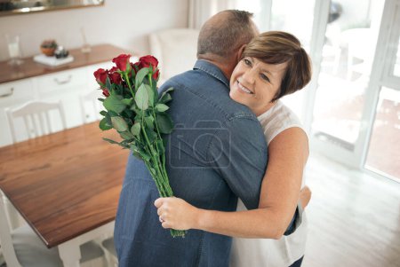 Photo for You still make my heart flutter. a mature wife hugging her husband for the gift of roses - Royalty Free Image