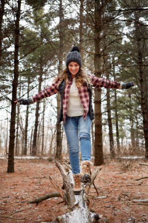 Photo for Hiking is an adventurers favourite hobby. a young woman walking on a tree log in the wilderness during winter - Royalty Free Image