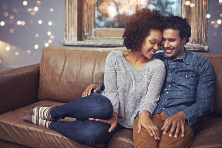 Photo for Hug, love and happy couple relax on a sofa, romantic and bonding on date night with bokeh. Interracial relationship, romance and man embrace woman on a couch, smile and chilling in a living room. - Royalty Free Image
