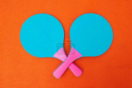 Photo for You dare challenge me. High angle shot of two table tennis bats placed together on top of an orange background inside of a studio - Royalty Free Image