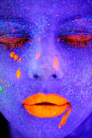 Neonfarbe, Schönheit und Frauengesicht in Nahaufnahme mit dunklem Hintergrund und kreativer Kosmetik. Glühen, schwärmen Make-up und psychedelische Kosmetik eines weiblichen Modells mit einzigartigen und Kreativität mit Kunst im Studio.
