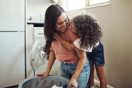 Photo for Someones really affectionate today. an adorable young girl hugging her mother while helping her with the laundry at home - Royalty Free Image