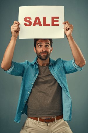 Photo for Man, hands and sale on billboard for advertising, marketing or branding against a grey studio background. Male person or realtor holding board, sign or poster for sales announcement or advertisement. - Royalty Free Image