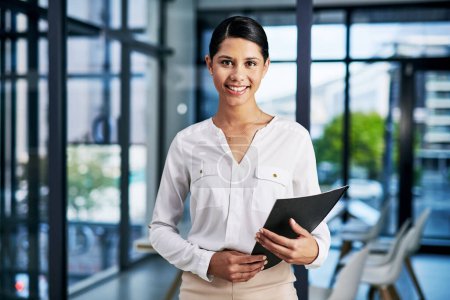 Photo for Im prepared for yet another successful business day. Cropped portrait of an attractive young businesswoman smiling while holding a file in a modern office - Royalty Free Image