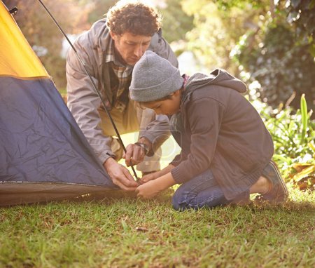 Photo for Dad, child and preparing tent for camping outdoor in nature on vacation while bonding in summer sunset. Father, boy and setting up camp, learning and getting ready in forest for adventure or travel - Royalty Free Image