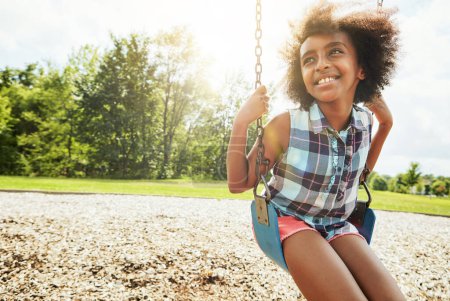 Foto de La inocencia de la infancia. una joven jugando en un columpio en el parque - Imagen libre de derechos