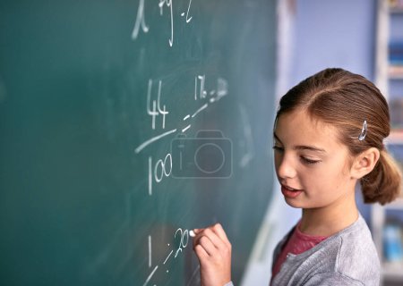 Photo for Shes almost got it. an elementary school girl writing on a blackboard in class - Royalty Free Image