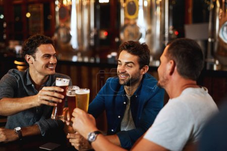 Téléchargez les photos : Bières, acclamations et hommes buvant avec des amis lors d'un événement social dans un restaurant avec bonheur. Alcool, verres et pain grillé dans un pub à l'apéro avec sourire et conversation avec boissons et célébration. - en image libre de droit