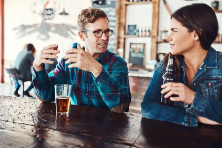 Téléchargez les photos : Il y a toujours quelqu'un d'intéressant à rencontrer dans un bar. un jeune homme et une jeune femme heureux qui boivent des bières dans un bar - en image libre de droit