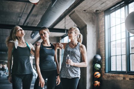 Foto de Ponerse al día después de clase de fitness. Retrato recortado de tres mujeres atractivas y atléticas haciendo ejercicio en el gimnasio - Imagen libre de derechos
