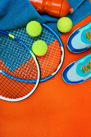 Photo for Done with my training for the day. High angle shot of tennis essentials placed on top of an orange background inside of a studio - Royalty Free Image