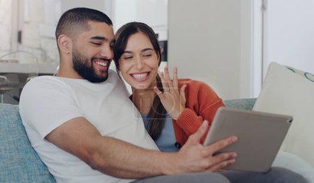 Photo for Engagement, announcement and a couple on a video call from a sofa in the living room of their home together. Smile, proud or excited with a happy man and woman sharing good news about their marriage. - Royalty Free Image