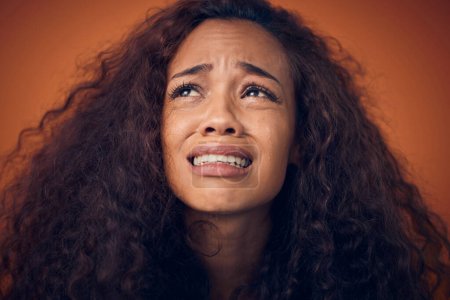Foto de Mujer, llanto y cara triste en estudio con ansiedad, problemas de salud mental y depresión. Imagen de una mujer africana sobre un fondo marrón para llorar emoji, psicología y corazón roto con lágrimas. - Imagen libre de derechos
