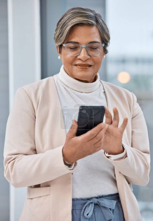 Photo for Mature woman, phone and typing in office, checking email or social media for business website. Cellphone, scroll and businesswoman ceo surfing internet for networking, search and reading online post - Royalty Free Image