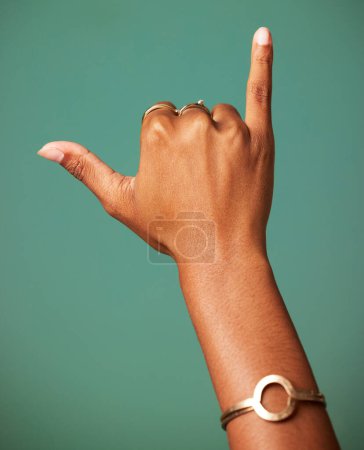 Foto de Mujer, Shaka signo y mano en el estudio para el saludo surfista, lenguaje de señas y la libertad. Emoji, icono y símbolo de una persona femenina con joyas y manos para el respeto y colgar suelto sobre un fondo verde. - Imagen libre de derechos