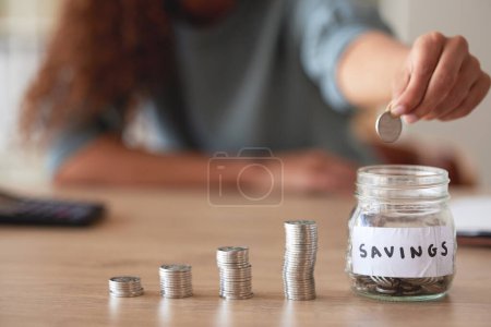 Photo for Hand, savings jar and money with finance and budget, future financial planning with investment and coins on a table. Woman saving, payment and economy, growth and development, cash in glass container. - Royalty Free Image