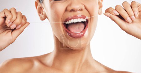 Téléchargez les photos : Sourire, dents dentaires et de la soie dentaire femme en studio pour l'hygiène, le bien-être ou une haleine fraîche sur fond gris. Mains, fil dentaire et dame se détendent avec la bouche, la dent ou le nettoyage pour les soins buccodentaires ou la prévention de la cavité. - en image libre de droit