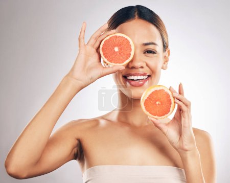 Photo for Portrait, skincare and happy woman with grapefruit in studio fo organic, cosmetic or treatment on grey background. Citrus, face and female model with fruit for eco, vegan or skin detox with vitamin c. - Royalty Free Image