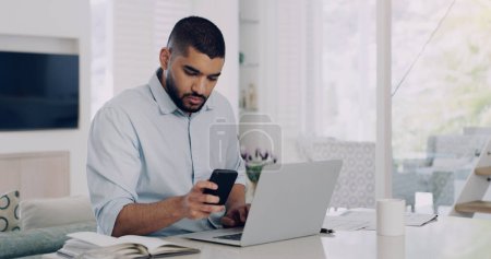 Photo for Man, remote work and smartphone at laptop in home for reading notification, digital planning and online information. Male freelancer, cellphone and working on computer, internet and check mobile app. - Royalty Free Image