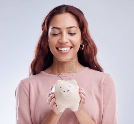 Photo for Finance, portrait or happy girl with a piggy bank for financial wealth or savings on white background. Smile, investment or woman smiling or investing cash or budget in tin for safety or security. - Royalty Free Image