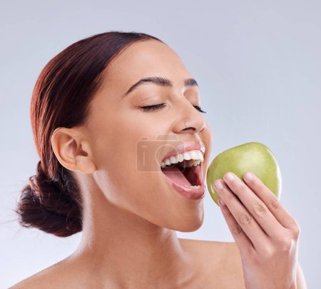 Photo for Apple, bite or happy woman in studio eating on white background for healthy nutrition or clean diet. Smile or hungry beautiful girl with open mouth for natural organic green fruits for wellness. - Royalty Free Image