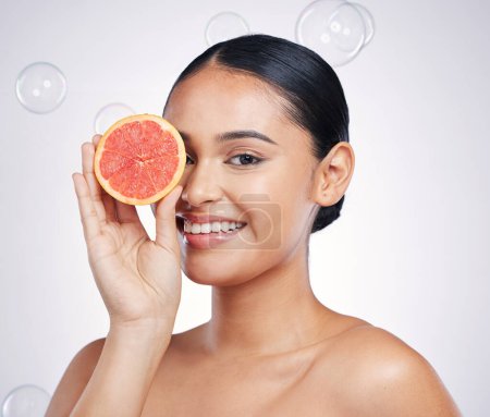 Photo for Face, grapefruit and beauty portrait of a woman in studio for glow and natural dermatology. Female person with a fruit in hand and bubbles for facial detox, vitamin c and health on a white background. - Royalty Free Image