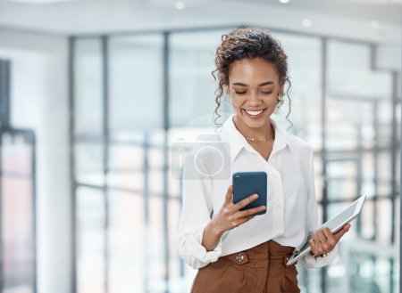 Foto de Negocios, mujer y lectura en teléfono móvil con tablet en la oficina con una sonrisa para la comunicación en línea. Mujer profesional, tecnología y mecanografía en una empresa para conversar en internet - Imagen libre de derechos