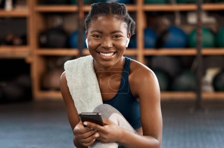 Foto de Mujer negra feliz, fitness y retrato con teléfono para redes sociales, comunicación o networking en el gimnasio. Rostro de una mujer africana escribiendo, enviando mensajes de texto o chateando en un teléfono inteligente después del ejercicio. - Imagen libre de derechos