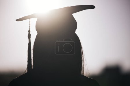 Photo for Graduation, education and silhouette of a student woman outdoor on university campus with lens flare. Future, college and scholarship with a female graduate standing outside at an event from the back. - Royalty Free Image