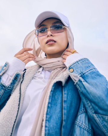 Photo for Portrait, fashion or low angle with a muslim woman outdoor in a cap, sunglasses and scarf for contemporary style. Islam, faith or hijab with a trendy young arab person posing alone in modern eyewear. - Royalty Free Image