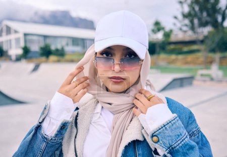 Téléchargez les photos : Portrait, mode ou lunettes de soleil avec une femme islam en plein air dans un chapeau et une écharpe pour un style contemporain. Arabe, visage et hijab avec une jeune femme musulmane à la mode posant dehors dans des lunettes modernes. - en image libre de droit