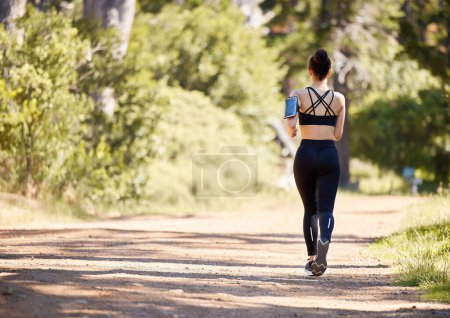 Photo for Woman, fitness and running in nature for exercise, cardio workout or training in the outdoors. Rear view of fit, active and sports female person, athlete or runner exercising for healthy wellness. - Royalty Free Image