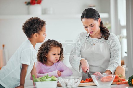 Photo for Cooking, food and cutting with family in kitchen for health, nutrition and support. Diet, vegetables and dinner with mother and children with meal prep at home for wellness, salad and learning. - Royalty Free Image