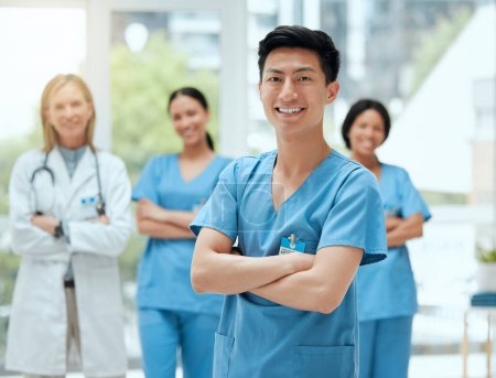 Photo for Portrait, medical and an asian man nurse arms crossed, standing with his team in a hospital for healthcare. Leadership, medicine and teamwork with a male health professional in a clinic for treatment. - Royalty Free Image