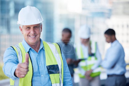 Photo for Portrait, thumbs up and a senior man construction worker outdoor on a building site with his team in the background. Management, motivation and support with a mature male architect saying thank you. - Royalty Free Image