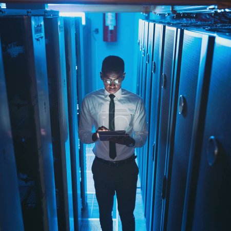 Photo for I can code in my sleep. a young IT specialist standing alone in the server room and using a digital tablet - Royalty Free Image