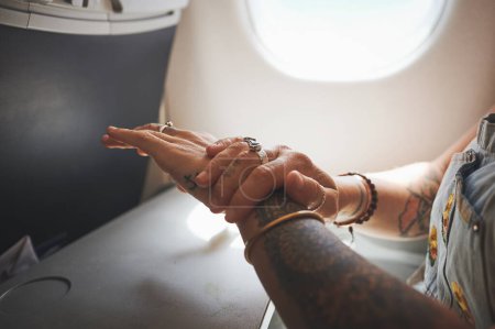 Foto de La seguridad es clave. una mujer desinfectando sus manos en el avión - Imagen libre de derechos