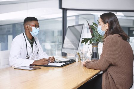 Photo for Is there any medication youre allergic to. a young doctor sitting with his patient and wearing his face mask during a consultation in the clinic - Royalty Free Image