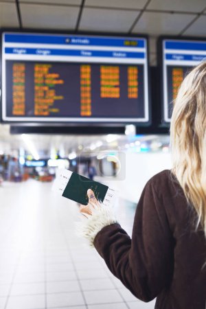 Téléchargez les photos : Le voyage commence. une femme vérifiant l'heure de son vol à l'aéroport - en image libre de droit