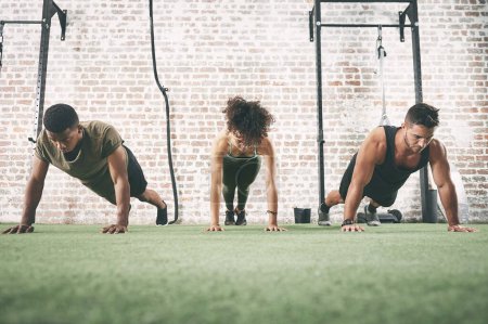 Photo for Once you see see results, it becomes an addiction. a fitness group doing push-ups at the gym - Royalty Free Image
