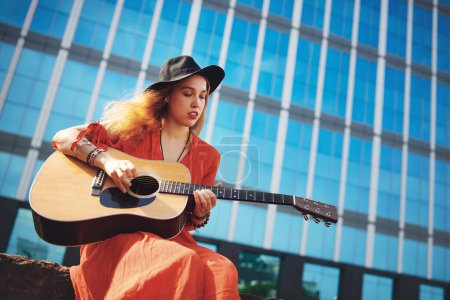 Photo for Did you know that your guitar keeps the bad days at bay. a beautiful young woman playing the guitar while out in the city - Royalty Free Image