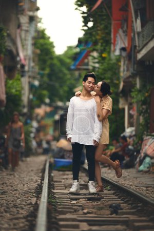 Foto de Sus besos hacen sonreír a mi corazón. una joven pareja compartiendo un momento romántico en las vías del tren en las calles de Vietnam - Imagen libre de derechos
