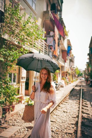 Téléchargez les photos : Suivez votre cœur vers le bonheur. une jeune femme marchant sur les voies ferrées dans les rues du Vietnam - en image libre de droit