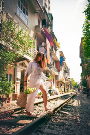 Foto de Donde está tu sentido de la aventura. una joven caminando en las vías del tren por las calles de Vietnam - Imagen libre de derechos