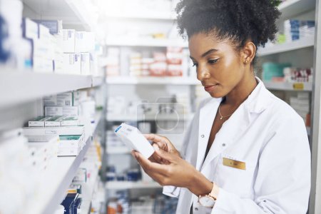 Téléchargez les photos : S'assurer que le médicament est sûr pour son client. un pharmacien lisant l'étiquette d'un produit dans une pharmacie - en image libre de droit