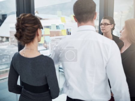 Photo for Considering all their options to ensure they make smart choices. a group of businesspeople brainstorming with notes on a glass wall in an office - Royalty Free Image