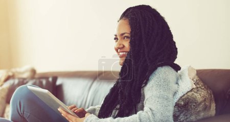 Téléchargez les photos : Découvrir les joies de passer du temps seul. une jeune femme utilisant sa tablette tout en se relaxant à la maison - en image libre de droit