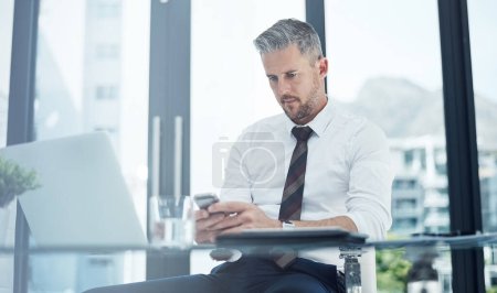 Photo for Its vital to maintain consistent contact with your networks. a corporate businessman texting on a cellphone while working in an office - Royalty Free Image